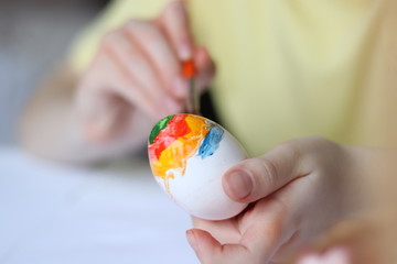 Child is painting eggs with paints on Easter holiday