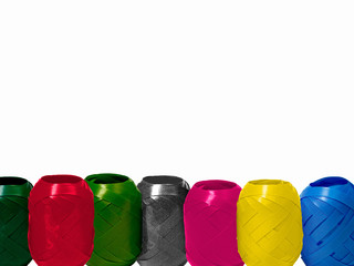 seven rolls of ribbon for decorating gifts in different colours in front of  a white background, copy space