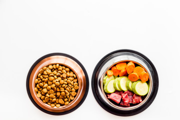 Healthy feed for cats and dogs. Bowls full of dry feed, meat and vegetables on white background top-down copy space