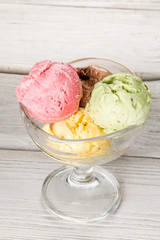 Ice cream in a glass bowl shot on a wooden white background