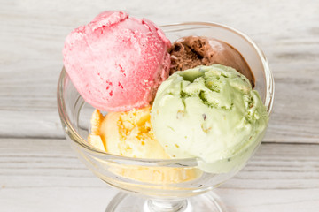 Ice cream in a glass bowl shot on a wooden white background