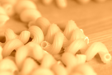 Spiral pasta scattered on a wooden surface close-up. Healthy food background brown color toned