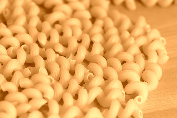 Spiral pasta scattered on a wooden surface close-up. Healthy food background brown color toned