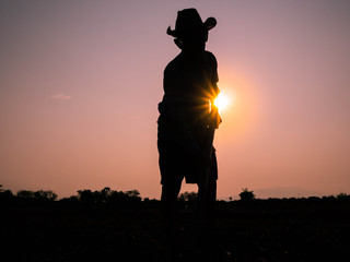 Silhouette of Elderly Asian farmers shoveling and prepare the soil with a spade for planting on sunset background.