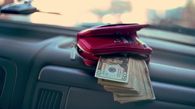 Wallet sitting on dash of car with cash money hanging out