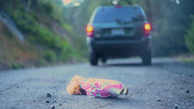 Car backing up to get dropped lost doll on road