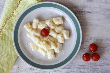 White plate of hot creamy potato gnocchi served with cherry tomatoes/ Flatware/ Food background