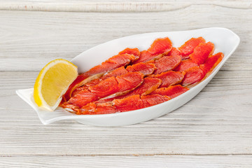 Sliced sockeye salmon on a white plate with lemon