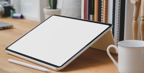 Close up view of blank screen tablet with office supplies and coffee cup