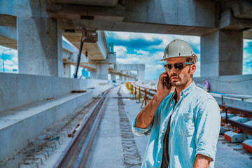 A senior engineer under inspection and checking construction process railway and checking work on railroad station platform .Engineer wearing safety uniform and safety helmet in work.