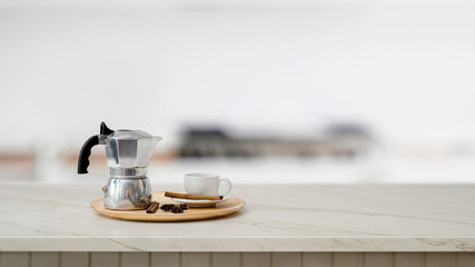 Close up view of mock pot and coffee cup on marble desk with blurred kitchen