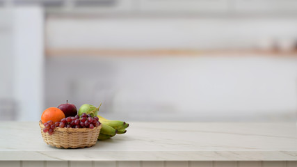 Close up view of fruit basket and copy space on marble desk with blurred kitchen room