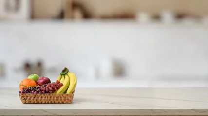Fotobehang Vruchten Close up view of fruit basket on marble desk with blurred kitchen room  © bongkarn