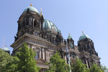 View from below of the old stone Cathedral with green domes, sculptures, columns and stucco