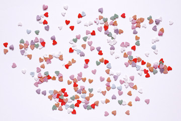 Confetti of small multicolored hearts on a white backgroun