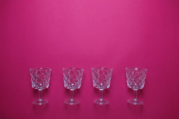 Obraz premium Four wine glasses on pink background with copy space.