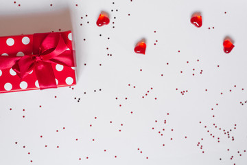 Gift with red bow, glass hearts on white background with confetti Background of Valentine's day