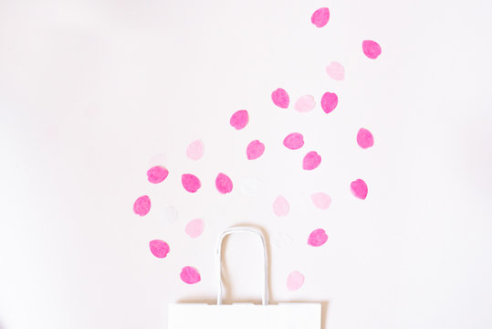 Gift bag with scattered paper rose petals on a white background. Valentine's day is a real concept.