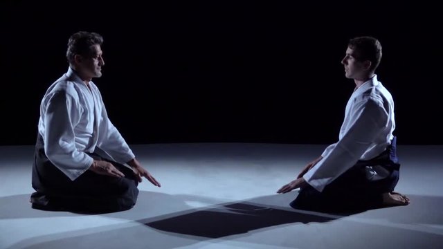 Two Masters martial arts Aikido Bow to Each Other. Shot Isolated on Black and White Background. Slow motion. Close up.