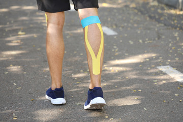 Fototapeta na wymiar Sporty man with physio tape applied on leg outdoors