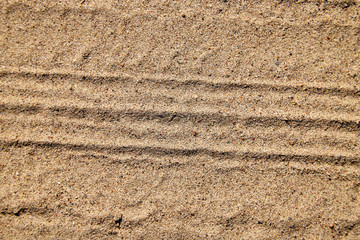 Tyre prints on the yellow sand. Nature background or texture