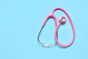 Modern stethoscope on color background