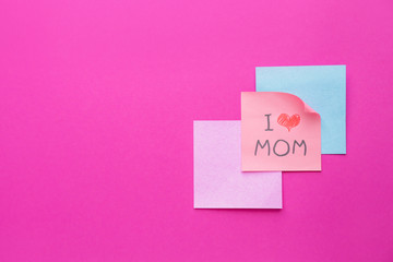 Paper sheets with text I LOVE MOM on color background