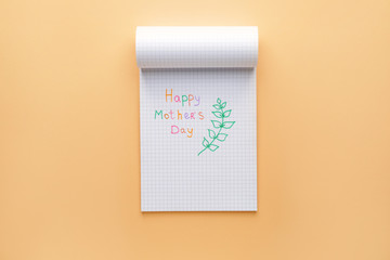 Notebook with text HAPPY MOTHER'S DAY on color background