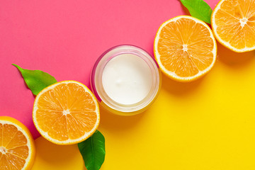 Cosmetic bottle with sliced citrus fruits on bright pink background