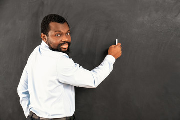 African-American teacher writing on blackboard in classroom