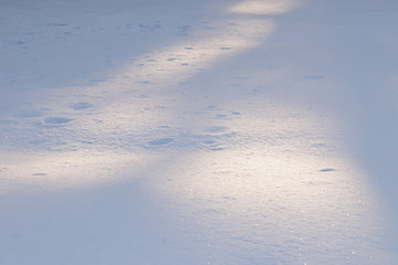 Winter background: snow in the rays of the evening sun in yellow and blue colors and glitter.