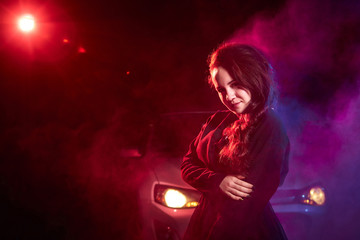 Portrait of chubby teen girl near car illuminated by red light and black background