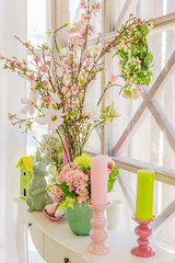 Easter interior decoration. Beatuful composition with candles. eggs, rabbit, birds house and blooming apple branches.