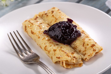 Homemade pancakes with cream cheese and berry jam on a plate, selective focus. Wooden table