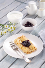 Homemade pancakes with cream cheese and berry jam on a plate, selective focus. Wooden table