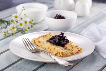 Homemade pancakes with cream cheese and berry jam on a plate, selective focus. Wooden table