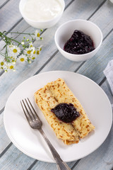 Homemade pancakes with cream cheese and berry jam on a plate, selective focus. Wooden table