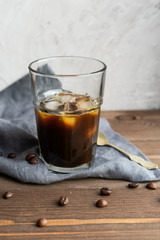 Black iced coffee on wooden background