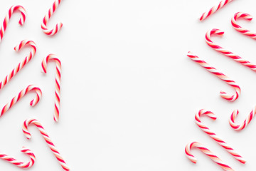 Christmas candies frame - cane with red and white stripes - on white background top-down copy space