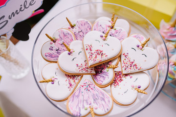Gingerbread cookies covered with multi colored icing in pale pastel colors shaped as heart unicorn.Birthday cakes