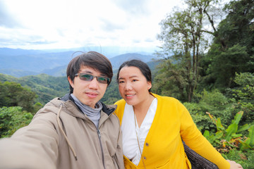 Asian couple taking selfie on view point with beautiful nature background