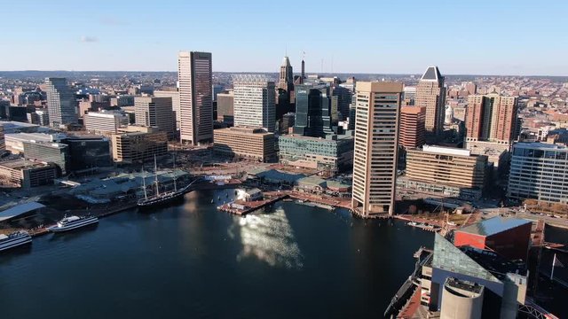 High aerial dolly shot of Baltimore City and Inner Harbor on beautiful day under blue sky