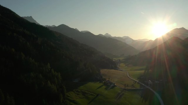 Flying over the stunning Zell Pfarre Valley in Austria with the beautiful yellow sun rising from behind the mountains - Aerial shot