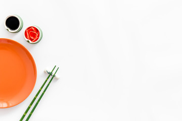 Tableware for sushi and rolls. Plate, chopsticks, bowls with ginger and sause on white background top-down copy space
