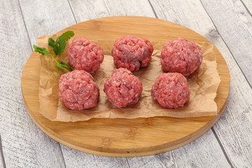 Raw meatball over wooden background