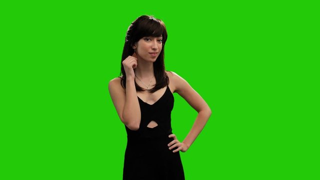 Beautiful slim female model posing sensual on green screen in black dress