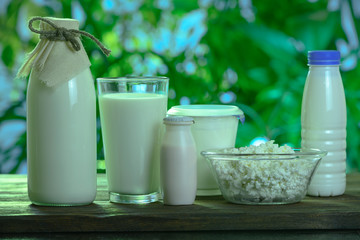 dairy products stand on a wooden table against the background of nature
