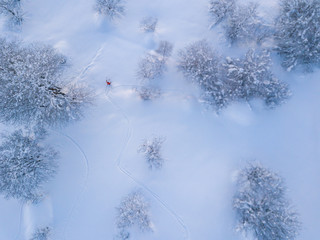 Aerial view of backcountry freeride skier leaving traces in powder snow. Concept of backcountry mountaineering.