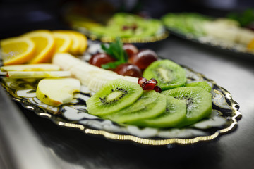 Sliced fruits on a beautiful plate against the background of the restaurant’s kitchen