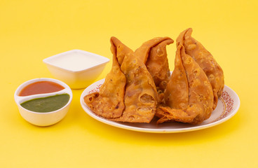 Indian Street Food Samosa or Samosas is a Crispy And Spicy Triangle Shape Snack Which Has Crisp Outer Layer of Maida & Filling of Mashed Potato, Peas And Spices. Served With Chutney, Ketchup or Curd